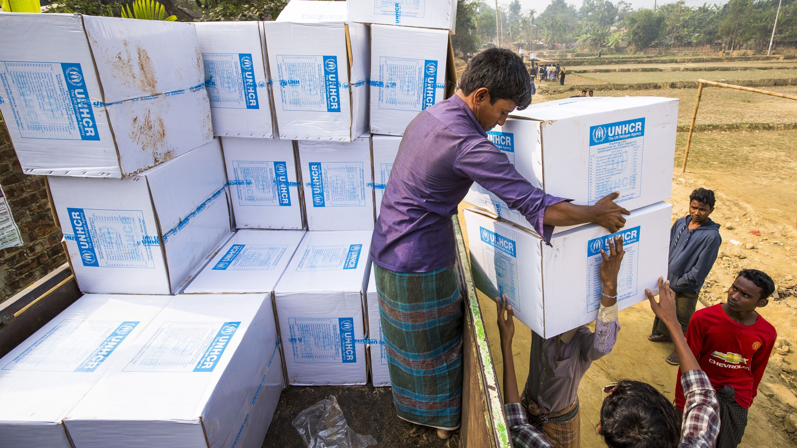 Rohingya men unload supplies from UNHCR 